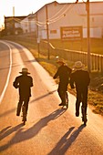 Amish children ride push scooters to church during sunrise in Bird in Hand, PA