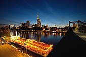 The Frankfurt am Main skyline and boat restaurants moored on the Main river, seen from Alte brücke bridge at sunset, Germany, Europe