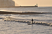 Surfer On A Rough Sea With The Treport Lighthouse In The Background, Mers-Les-Bains, Bay Of Somme, Somme (80), France