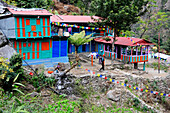 Nepal Annapurna ring hikker walking in front of a colorfull lodge decorated with prayers'flags