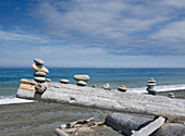 Dungeness Spit near Sequim, a view over the sea, from the beach. A pile of wood, with small stacks of rocks balanced on a wooden log.