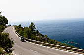 Motorradfahrer auf kurviger Küstenstraße am Mittelmeer, Estellencs, Mallorca, Spanien