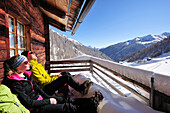 Junge Frau und junger Mann sonnen sich vor einer Almhütte, Kreuzspitze, Osttirol, Tirol, Österreich