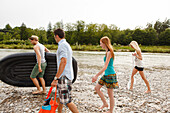 Young people with a rubber dinghy on the Isar riverbank, Munich, Bavaria, Germany