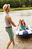 Young people with a rubber dinghy at Isar river, Munich, Bavaria, Germany