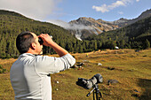 Ranger mit Fernglass im Schweizer Nationalpark am Ofenpass, Zernez, Unterengadin, Graubünden, Schweiz, Europa