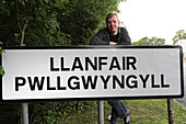 Ortsschild von Llanfair Pwllgwyngyll und Fotograf Tilman Schuppius, Nord Wales, Großbritannien, Europa