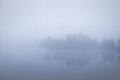 peninsular with power pole at forest lake surrounded by fog, Leipheim around Günzburg, Schwaben, Bavaria, Germany