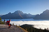 Hiker looking over the fog in the valley onto Watzmann and Hochkalter, Berchtesgaden region, Berchtesgaden National Park, Upper Bavaria, Germany, Europe