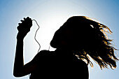 Silhouette of Pretty girl listening music on mobile at Ebro riverside of ExpoZaragoza outdoors area, Saragossa, Aragon, Spain