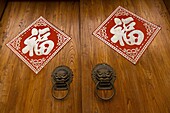 Traditional Chinese door with red lanterns and good luck signs in the restored hutong district of Wudaoying in Beijing, China