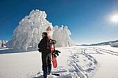Schneeschuhwanderer mit Snowboard vor schneebedeckten Buchen, Schauinsland, Freiburg im Breisgau, Schwarzwald, Baden-Württemberg, Deutschland