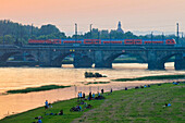 Sonnenuntergang Elbe mit Marienbrücke, Menschen auf Elbwiesen, Dresden, Sachsen, Deutschland