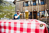Mann trinkt ein Bier auf einer Terrasse, Johannishütte, Virgental, Tirol, Österreich