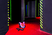 Laser game playing space, with walls and narrow spaces lit up by lasers, A suit of body armour with a laser gun weapon