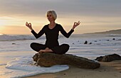 Mature Woman In Yoga Position On Seashore At Sunset