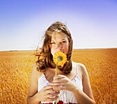Young Woman Smelling Flower In Field