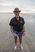 Einheimischer sammelt bei Ebbe Muscheln am Strand, Karamea, Westküste, Südinsel, Neuseeland
