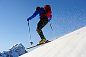 Backcountry skier downhill skiing from Brechhorn, Grosser Rettenstein in background, Kitzbuehel Alps, Tyrol, Austria