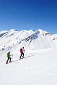 Two backcountry skiers ascending to Brechhorn, Grosser Rettenstein in background, Kitzbuehel Alps, Tyrol, Austria