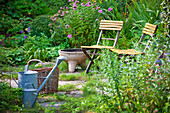 Watering can with a basket and two chairs, garden in summer, Vienna, Austria