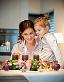 Mother and daughter (4 years) lighting candle on an Advent wreath