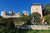 Couple on electric bikes in front of Kastelbell castle, E-bikes, Bozen, South Tyrol, Italy
