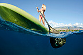 Hawaii, Maui, Woman stand up paddling in ocean just off Canoe Beach, Over/under view.