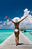 French Polynesia, Tuamotu Islands, Rangiroa Atoll, Woman walking down ocean pier, View from behind.