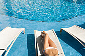 Hawaii, Woman lounging at hotel poolside, Legs and midriff.