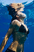Hawaii, Big Island, Honaunau Bay, Young woman exhales as she swims to ocean surface.