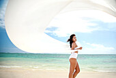 Hawaii, Oahu, Lanikai Beach, Beautiful young woman on beach with white fabric blowing in the wind.