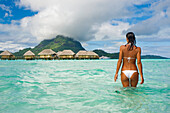 French Polynesia, Tahiti, Bora Bora, Woman in the ocean with bungalows in the background.