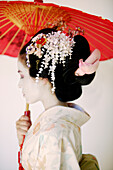 Side profile portrait of a Maiko holding umbrella.