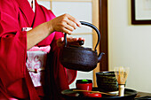 Close up of geisha pouring tea at tea ceremony.