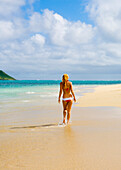 Hawaii, Oahu, Lanikai, Bikini-clad girl walking on beach, View from behind.