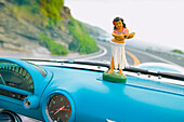 Plastic hula doll on the dashboard of a turquoise Thunderbird.