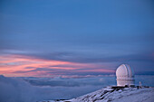 The Canada-France-Hawaii Observatory in the evening light on Mauna Kea on hawaii. A building on the mountain top with a dome, Telescope. Sunset., Canada-France Telescope