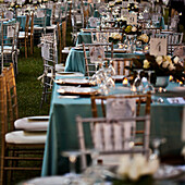A formal party. Small tables laid out with glasses, silver flatware and candles. Evening.  Under shady trees. Elegant event. Lanterns., Savannah, Georgia, USA, Outdoor Party