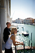 Junges Paar steht auf einem Balkon am Canal Grande, Venedig, Venetien, Italien