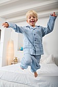 Four year old boy jumping off the bed