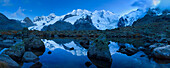 View from a pristine mountain lake at the end of the Morteratsch valley to the summits of Cambrena Piz, Piz Palu, Piz Zupo and Piz Bernina and their reflection, Engadin, Switzerland