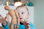 Boy (2 years) playing with a wooden mannequin, Leipzig, Saxony, Germany
