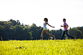 Couple running over a meadow, Upper Bavaria, Germany