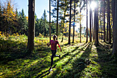 Young woman jogging through wood in autumn, Bavaria, Germany