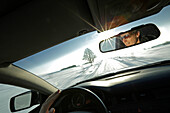 Man driving a car along a snow-covered street, Bavaria, Germany