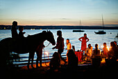 Adults and children with torches at lakeshore, lake Starnberg, Bavaria, Germany