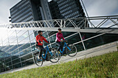 Couple riding e-bikes, Munich, Bavaria, Germany