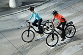 Couple riding e-bikes, Munich, Bavaria, Germany