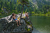 Young people sunbathing on a rock at lake Dieslingsee, Turracher Hoehe, Styria, Austria